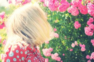 A person standing and looking at a flowering plant.