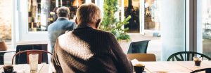 Older man sitting in a cafe drinking coffee.
